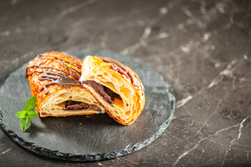 Freshly baked croissant filled with dark chocolate, topped with chocolate flavoured fondant and dusted with icing sugar