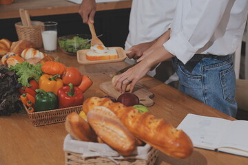 Handsome man sitting near his wife at kitchen. Family couple see social media, surf the web while sitting at kitchen table with generic laptop. Couple working with laptop at home