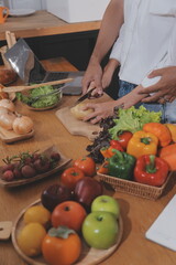Handsome man sitting near his wife at kitchen. Family couple see social media, surf the web while sitting at kitchen table with generic laptop. Couple working with laptop at home