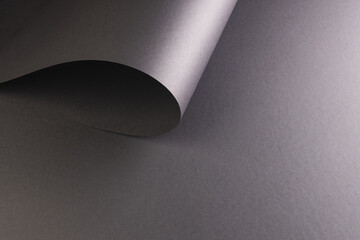 Close up of rolled up piece of black paper with copy space on black background
