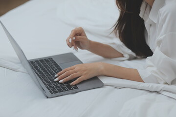 Naklejka premium Happy freelance asian woman work on tablet on the hotel bed on travel trip.