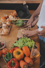 Handsome man sitting near his wife at kitchen. Family couple see social media, surf the web while sitting at kitchen table with generic laptop. Couple working with laptop at home