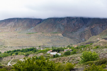 Dark Dramatic Desert Landscape with Foggy Mountains and Distant Houses in Muktinath, Mustang, Nepal