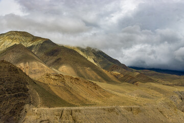 Dark Dramatic Desert Landscape with Foggy Mountains and Distant Houses in Muktinath, Mustang, Nepal