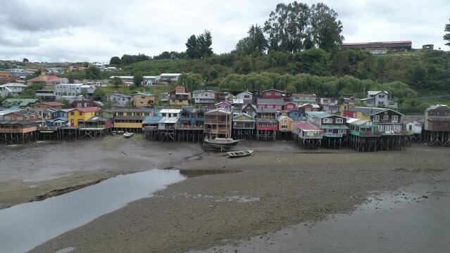 Aerial Panning Shot Of Stilt Houses At Coastline Against Cloudy Sky In City - Castro, Chile
