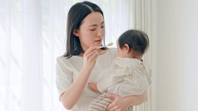 赤ちゃんに離乳食を食べさせるママ