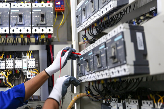 Electricity And Electrical Safety Maintenance Service System, Technician Hand Checking Electric Current Voltage At Circuit Breaker Terminal And Cable Wiring In Main Power Distribution Board.