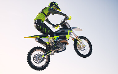 Jump, adventure and man on motorbike with blue sky for practice, training and extreme sports energy. Professional dirt biking challenge, person and danger with off road motorcycle stunt competition.