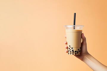 A hand holding takeaway plastic cup of delicious iced bubble milk tea and black pearls with copy space