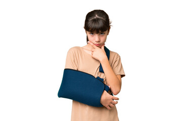 Little caucasian girl with broken arm and wearing a sling over isolated background thinking