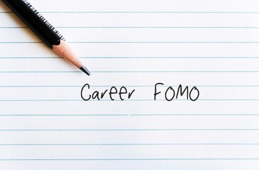 Pencil on office paper with handwritten text CAREER FOMO, means fear of missing out on a job opportunity,  the worry that everyone else is achieving and enjoying more success than you