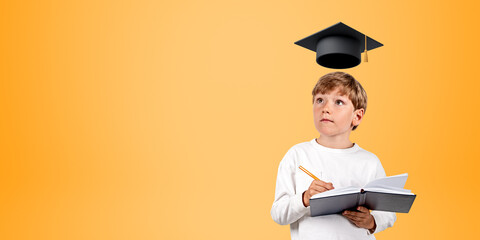 Serious schoolboy with notebook and mortarboard