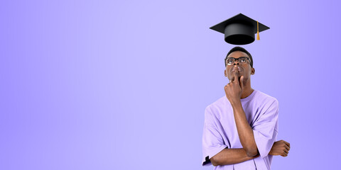 Thoughtful African man college student looking at mortarboard