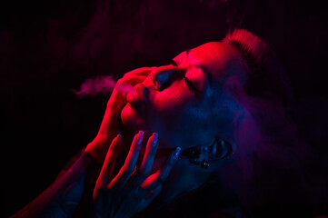 Sensual portrait of asian woman with short haircut smoking in neon light. 