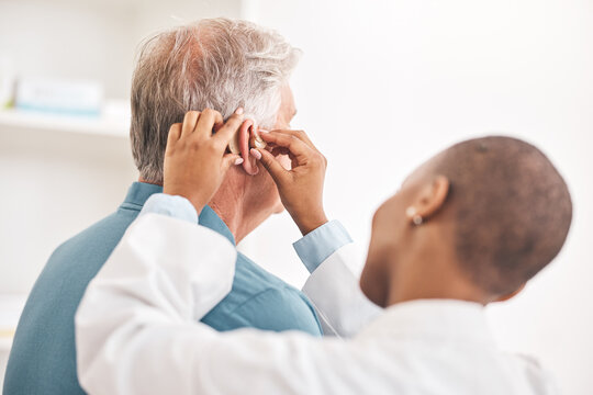 Doctor, Helping And Man With Hearing Aid, Technology Or Healthcare Or Medical Device Consultation For Deaf Patient With Tinnitus. Listening, Test And Exam Ear Tech With Nurse Or Senior Male In Clinic