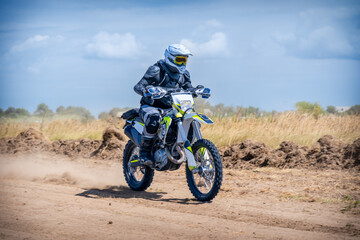 Fototapeta na wymiar Enduro bike racer driving on dirt motocross dust track