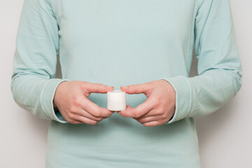 Woman's hands hold plastic jar (container). Cosmetic product.