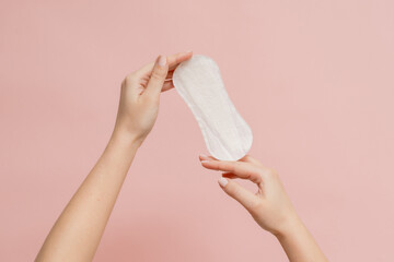 Sanitary napkin in woman's hand on pink background - obrazy, fototapety, plakaty