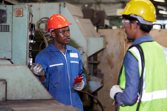 male african foreman training and teaching how to use machine control with workers in factory