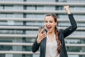 excited happy business woman celebrating looking at mobile phone