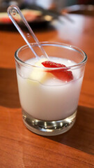 Vanilla jelly pudding with banana and strawberry fruit slice dessert appetizer in a small glass cup.