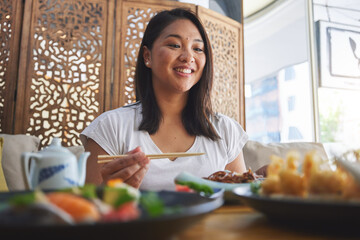 Asian, food and woman at a restaurant eating for dinner or lunch meal using chopsticks and feeling happy for nutrition. Plate, young and person enjoy Japanese cuisine, noodles or diet at a table