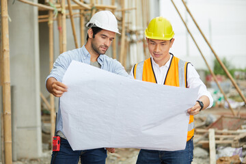 workers or architect holding plan blueprint paper at construction site