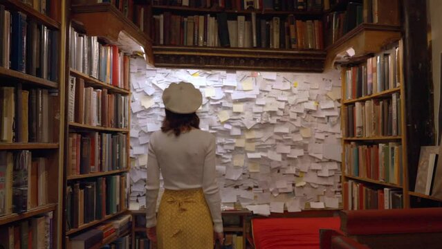Young girl looking at the wall with paper inscriptions in a bookstore in Paris
