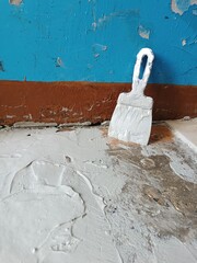 Renovation of old premises. Spatula in glue stands near old blue embossed wall. Laying floor tiles....