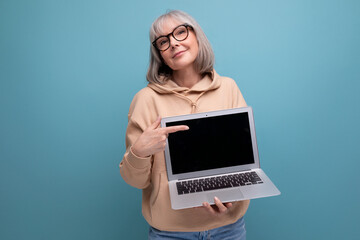 fashionable 60s business woman grandmother with gray hair working using laptop on studio background...
