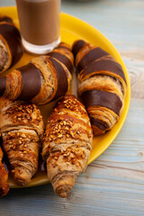 Chocolate croissants or croissant with nut crumbs on a plate. Delicious breakfast on the table. Tasty sweet baking dessert for coffee. Food background. Fresh buttery croissants rolls