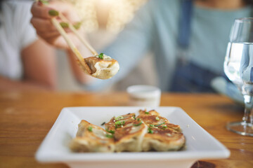 Table, plate and chopsticks with a dumpling at a restaurant for food, Asian culture or fine dining. Health, hungry and a person with dinner, eating lunch or enjoying a fried dish or cuisine at a cafe