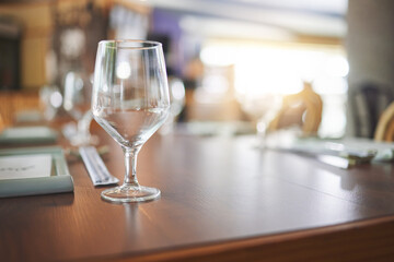 Bokeh, lunch and glass on a table at a restaurant for water, alcohol or wine. Dinner, crystal and tableware for a drink at a coffee shop or cafe during dinner for a luxury and fine dining experience