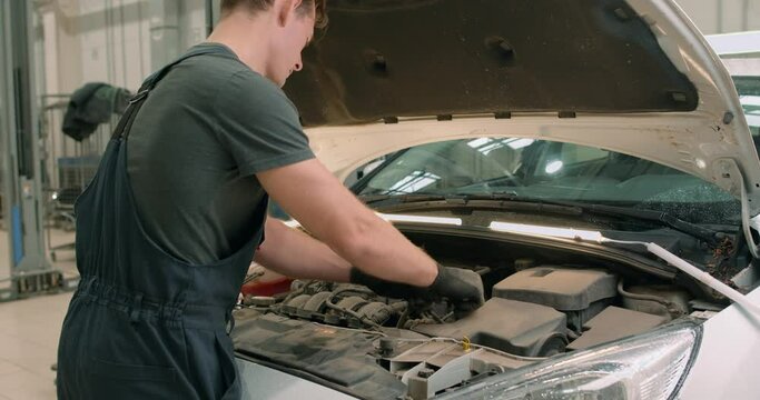 hardworking man repairing hood of car, check all missing atributes inside of automobile Slow motion back rare view Under the hood. People occupation and business job. Automobile technician