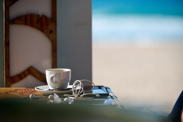 cup of coffee with headphones and phone on the table on a beach restaurant