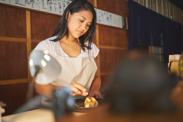 Chinese food, recipe and an asian woman in a sushi restaurant to serve a traditional meal for nutrition. Kitchen, cooking or preparation with a young female chef in an eatery for fine dining cuisine