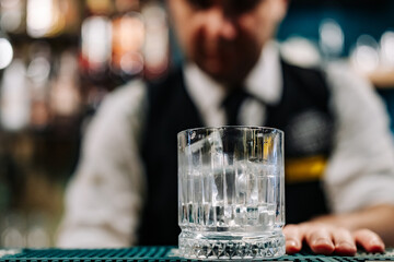 Ice cube in an empty glass on a bar counter in bar or pub