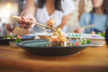 Sushi, hand and eating food with chopsticks at a restaurant for nutrition and health. Closeup of a hungry people with wooden sticks for dining, Japanese culture and cuisine with creativity on plate