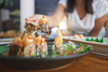 Hand, closeup and chopsticks in sushi restaurant for diet, fine dining and party with catering platter. Person, healthy fish and salmon with culture, traditional or fast food in diner, bar or store