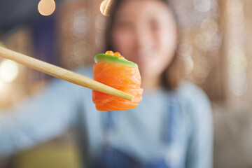Food, eating sushi and person with chopsticks at restaurant for nutrition and health. Closeup of a...