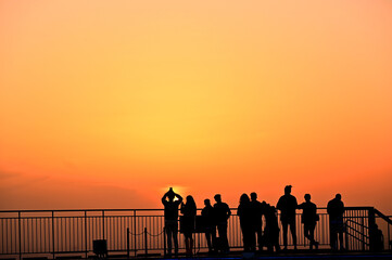 silhouette tourist group watching gold lighting sunset or sunrise sky background on skyscaper building