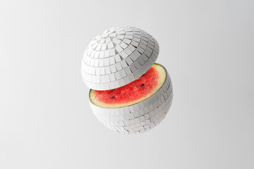 Creative concept of summer fruits. Mirrored white disco ball with watermelon inside on white background.