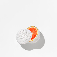 Creative fruit concept. White cut mirror ball with orange inside on white background.