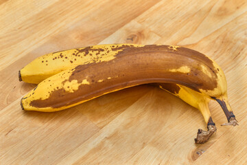 Kiść bardzo dojrzałych bananów na drewnianym blacie w kuchni 