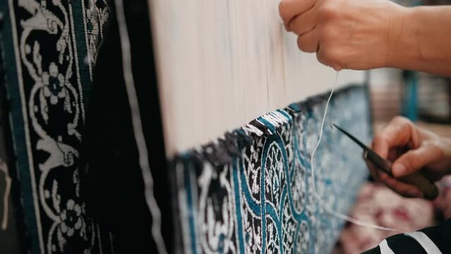 Woman weaves a traditional Arabic carpet of multicolored wool. Weaving and making handmade carpets close-up. Needlework. Handcraft