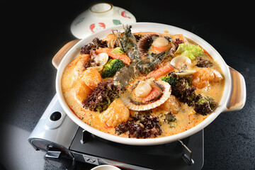 spicy mala laksa curry hot clay pot with seafood prawn, scallop, chicken meat, vegetable, noodle and chilli sambal thick gravy sauce in bowl on black table asian halal food cuisine menu for restaurant