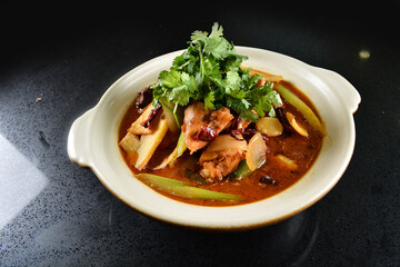 spicy mala laksa curry hot clay pot with seafood prawn, scallop, chicken meat, vegetable, noodle and chilli sambal thick gravy sauce in bowl on black table asian halal food cuisine menu for restaurant