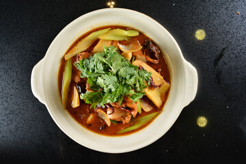 spicy mala laksa curry hot clay pot with seafood prawn, scallop, chicken meat, vegetable, noodle and chilli sambal thick gravy sauce in bowl on black table asian halal food cuisine menu for restaurant