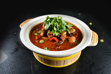 spicy mala laksa curry hot clay pot with seafood prawn, scallop, chicken meat, vegetable, noodle and chilli sambal thick gravy sauce in bowl on black table asian halal food cuisine menu for restaurant