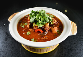 spicy mala laksa curry hot clay pot with seafood prawn, scallop, chicken meat, vegetable, noodle and chilli sambal thick gravy sauce in bowl on black table asian halal food cuisine menu for restaurant